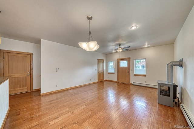 26 S Trailside Cir Unit A, Salida, CO 81201 - unfurnished living room featuring baseboard heating, a wood stove, ceiling fan, and light wood-type flooring