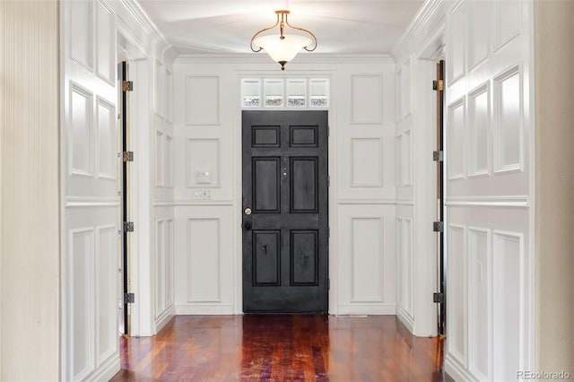 entryway featuring dark wood finished floors, a decorative wall, and crown molding