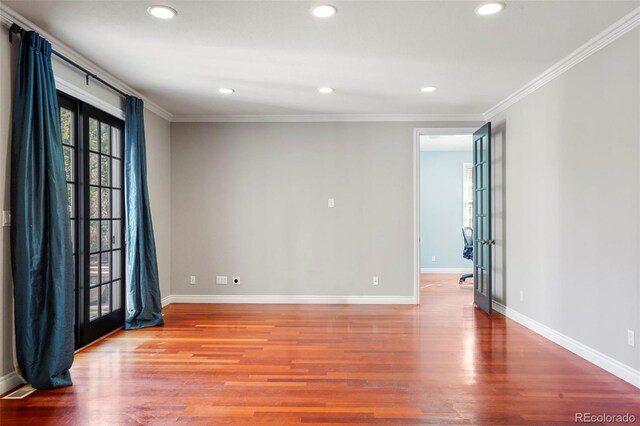 empty room with french doors, wood finished floors, and crown molding