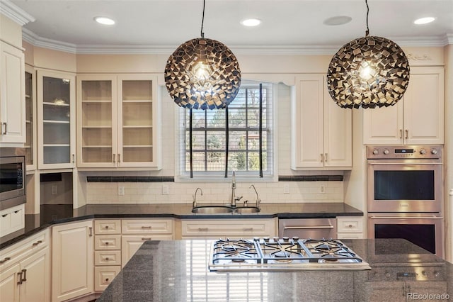 kitchen featuring glass insert cabinets, stainless steel appliances, crown molding, and a sink