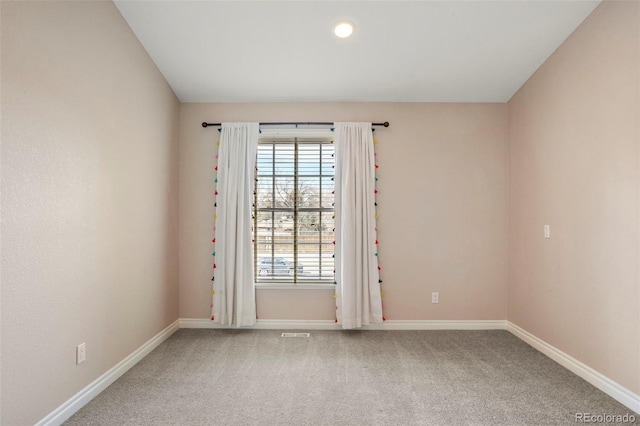 empty room featuring baseboards and light carpet