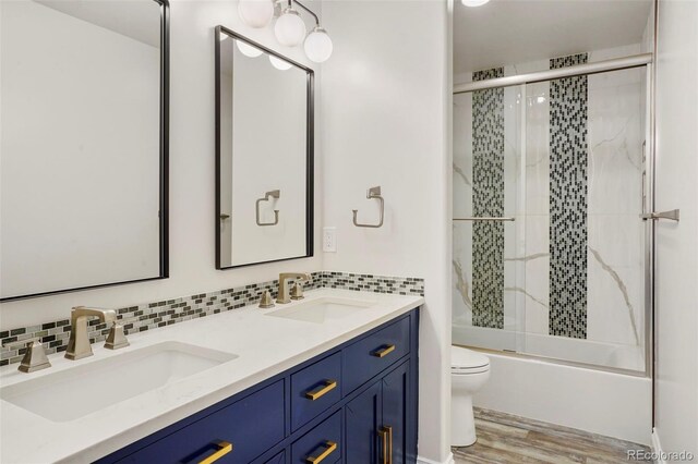 full bath with tasteful backsplash, wood finished floors, toilet, and a sink