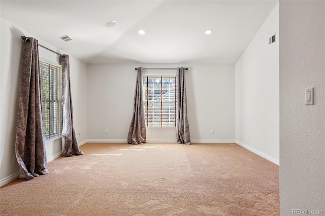 unfurnished room featuring baseboards, visible vents, and light carpet