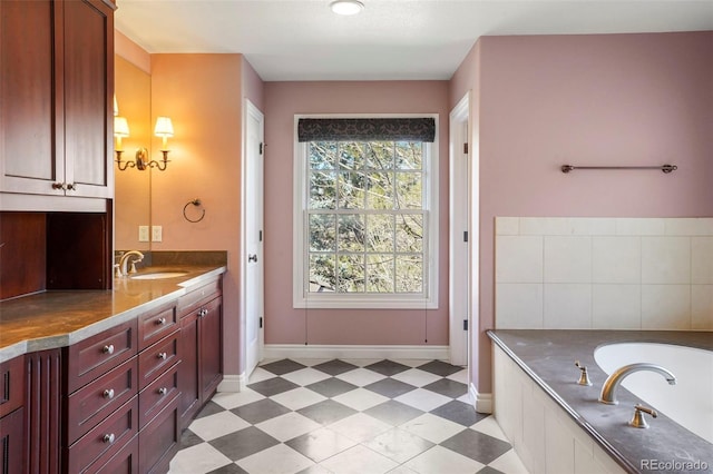 full bathroom with tile patterned floors, a washtub, vanity, and baseboards