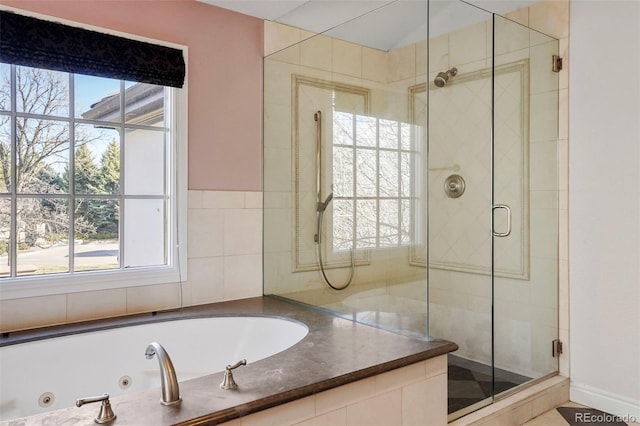 bathroom featuring a tub with jets and a shower stall