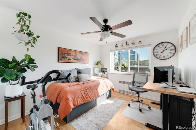 bedroom featuring radiator heating unit, baseboards, and wood finished floors