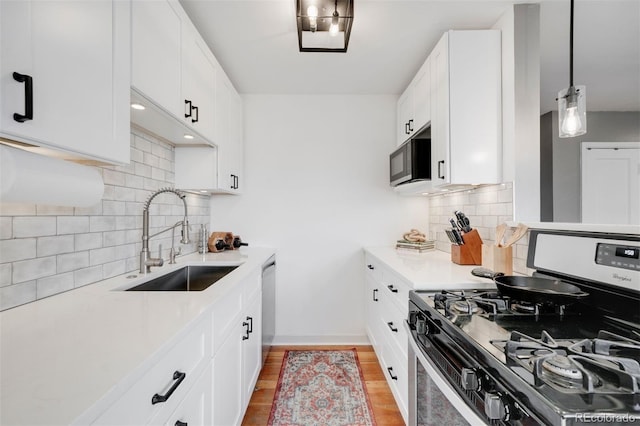 kitchen featuring baseboards, white cabinets, appliances with stainless steel finishes, light countertops, and a sink