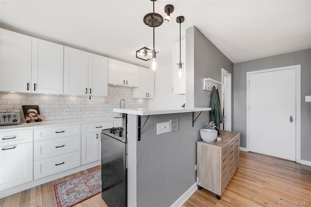 kitchen with a toaster, white cabinets, light countertops, decorative backsplash, and light wood finished floors