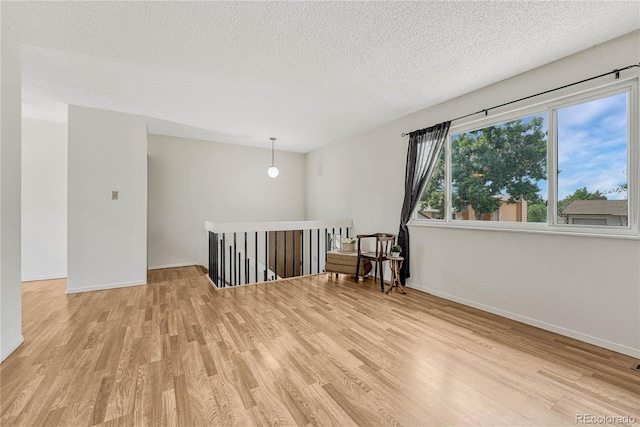 unfurnished room featuring light wood-type flooring and a textured ceiling