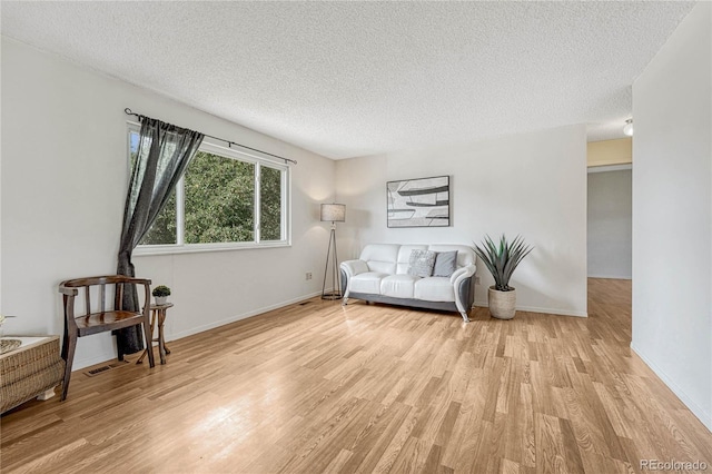 living area with a textured ceiling and light hardwood / wood-style flooring