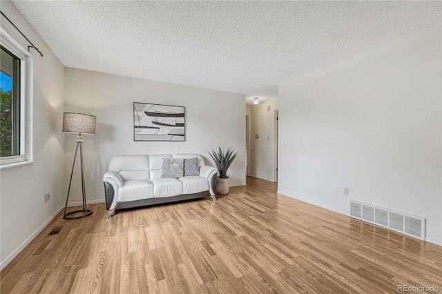 living room with light hardwood / wood-style floors and a textured ceiling