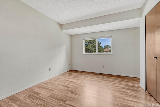 unfurnished bedroom with a textured ceiling and light hardwood / wood-style flooring