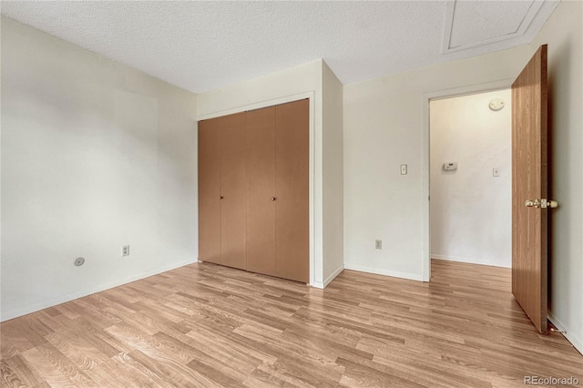 unfurnished bedroom with a textured ceiling, a closet, and light hardwood / wood-style flooring