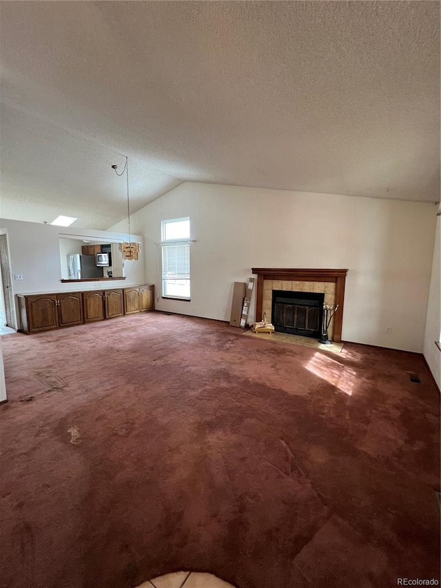 unfurnished living room featuring a fireplace, a textured ceiling, carpet floors, and vaulted ceiling