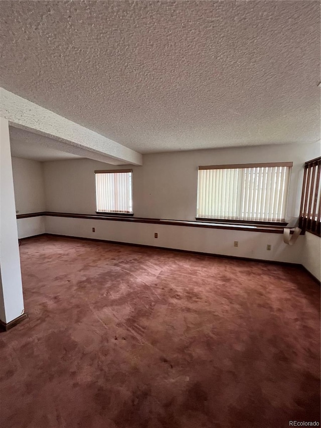 carpeted spare room featuring a healthy amount of sunlight and a textured ceiling