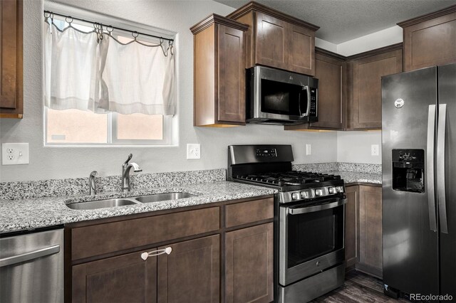 7568 Benecia Dr, Fountain, CO 80817 - kitchen with appliances with stainless steel finishes, a sink, light stone counters, dark wood-style flooring, and dark brown cabinetry