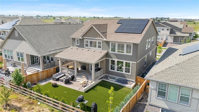 864 Clover Loop, Erie, CO 80026 - back of property with outdoor lounge area, a fenced backyard, board and batten siding, roof with shingles, and solar panels