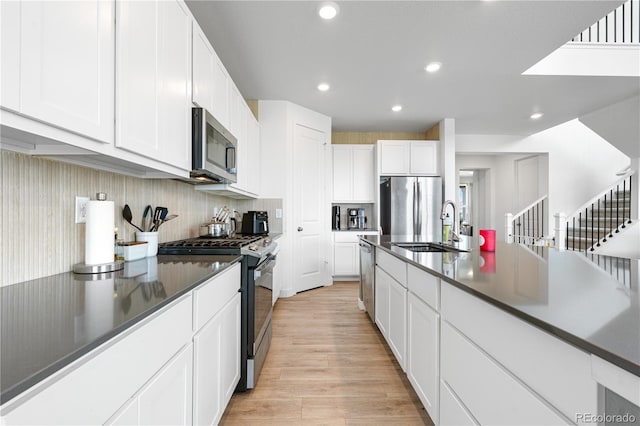 864 Clover Loop, Erie, CO 80026 - kitchen with stainless steel appliances, light wood finished floors, dark countertops, white cabinetry, and recessed lighting