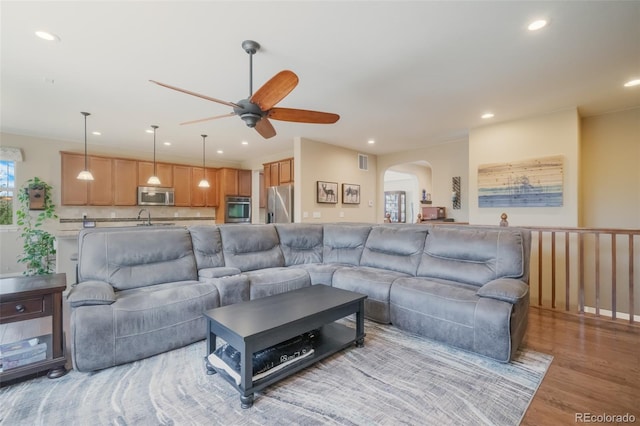 living room featuring ceiling fan, light hardwood / wood-style flooring, and sink