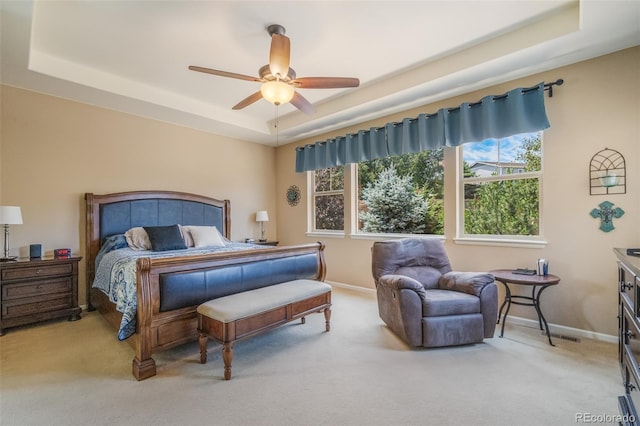 carpeted bedroom featuring ceiling fan and a raised ceiling