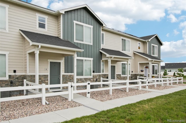 503 S Rollie Ave Unit 13C, Fort Lupton, CO 80621 - view of front facade with board and batten siding, stone siding, and a fenced front yard