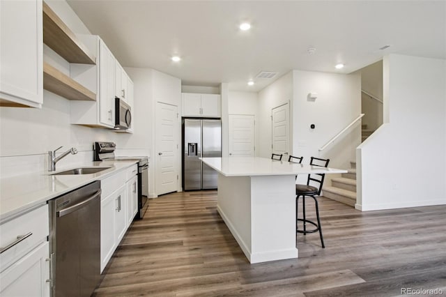 503 S Rollie Ave Unit 13C, Fort Lupton, CO 80621 - kitchen featuring stainless steel appliances, open shelves, a kitchen breakfast bar, dark wood-style floors, and a kitchen island
