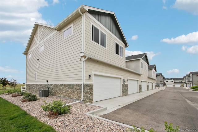 503 S Rollie Ave Unit 13C, Fort Lupton, CO 80621 - view of side of home with board and batten siding, an attached garage, stone siding, driveway, and a residential view