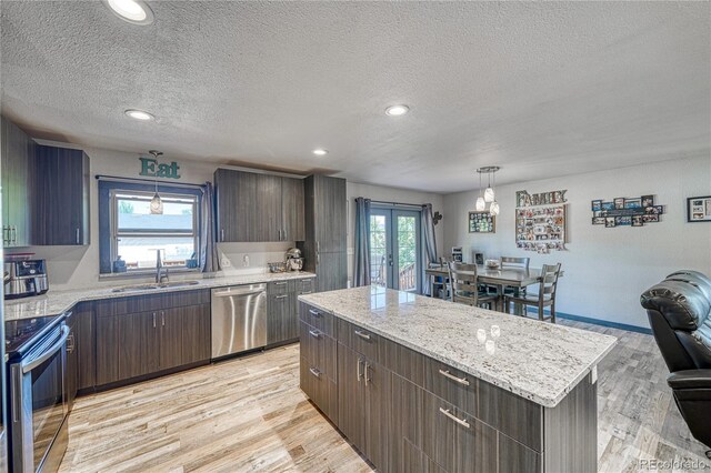 410 W 16th St, Salida, CO 81201 - kitchen featuring stainless steel appliances, a sink, a textured ceiling, light wood-style floors, and a kitchen island