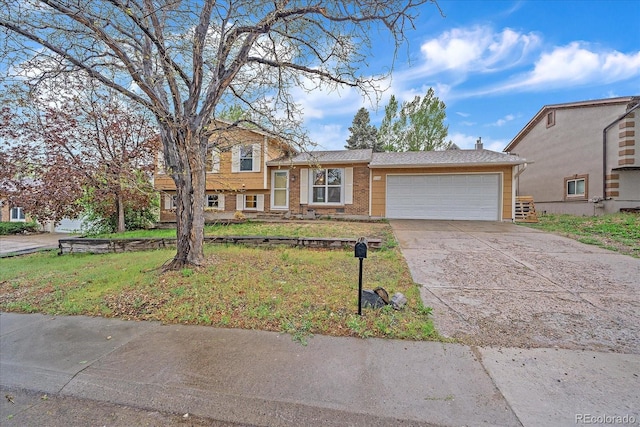 split level home featuring a garage, driveway, brick siding, and a front lawn