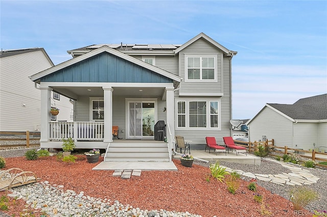 rear view of property featuring covered porch, solar panels, and a patio