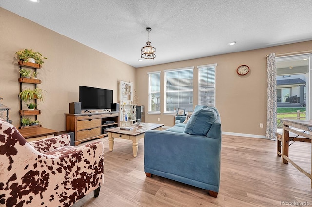 living room featuring a textured ceiling, light hardwood / wood-style flooring, and a notable chandelier