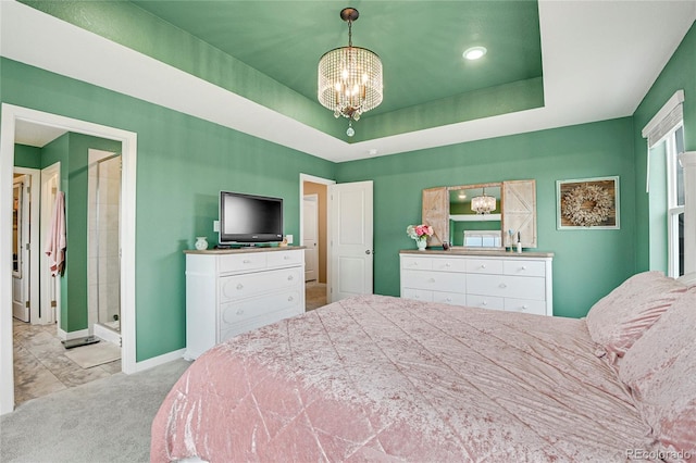 carpeted bedroom featuring a tray ceiling, connected bathroom, and a chandelier