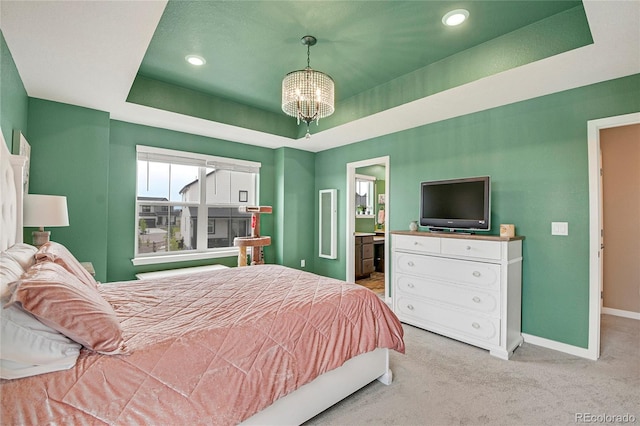 bedroom featuring connected bathroom, a chandelier, and light colored carpet