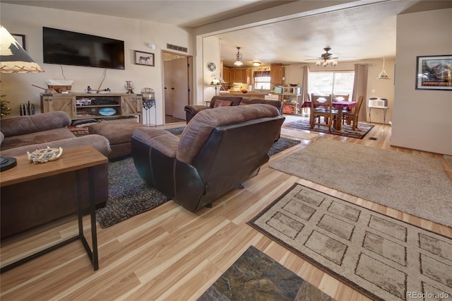 living room with ceiling fan and light hardwood / wood-style flooring