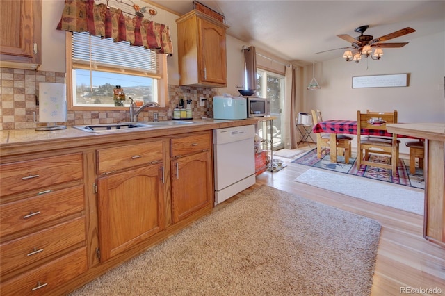 kitchen with dishwasher, light wood-type flooring, tasteful backsplash, and sink