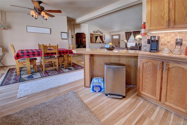 kitchen featuring ceiling fan, light brown cabinets, vaulted ceiling with beams, backsplash, and light wood-type flooring