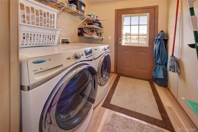 laundry room with separate washer and dryer and light hardwood / wood-style floors