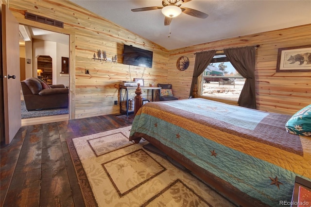 bedroom with dark hardwood / wood-style floors, wood walls, and lofted ceiling