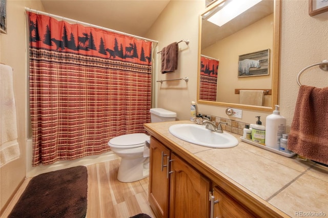 bathroom with vanity, toilet, wood-type flooring, and lofted ceiling with skylight