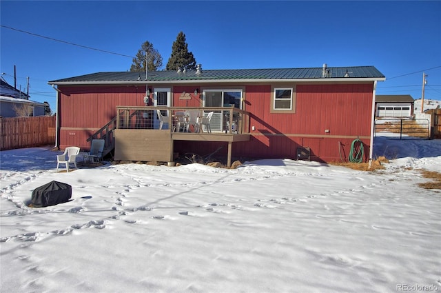 snow covered back of property with a wooden deck