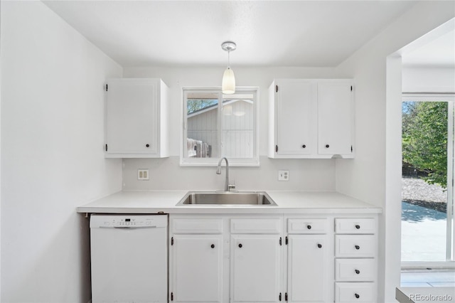 kitchen with white dishwasher, a sink, white cabinets, and light countertops
