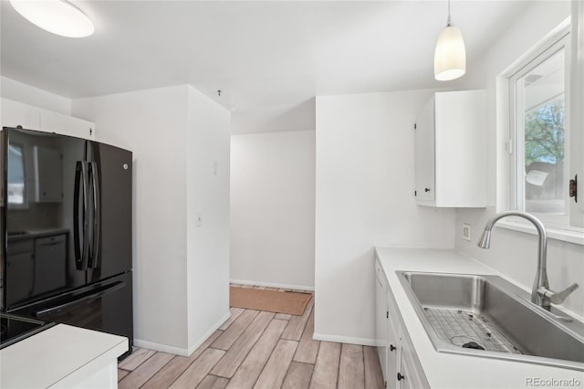 kitchen featuring freestanding refrigerator, a sink, and white cabinets