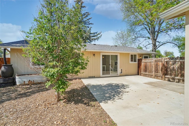 rear view of property featuring fence, a patio area, and a shingled roof