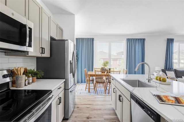 6117 Easton Cir, Frederick, CO 80504 - kitchen with appliances with stainless steel finishes, light wood-style floors, tasteful backsplash, and light stone countertops