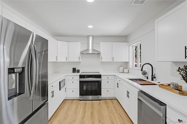3055 S Winona Ct, Denver, CO 80236 - kitchen featuring stainless steel appliances, wall chimney range hood, light wood-style flooring, light countertops, and white cabinetry