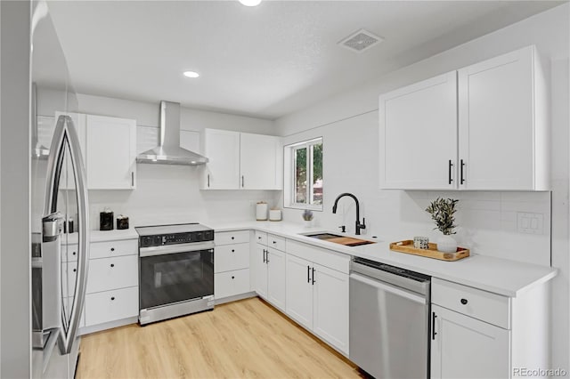 3055 S Winona Ct, Denver, CO 80236 - kitchen with stainless steel appliances, wall chimney exhaust hood, light wood finished floors, white cabinets, and light countertops