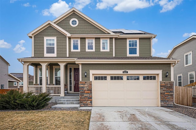 craftsman-style house featuring driveway, a garage, stone siding, covered porch, and roof mounted solar panels