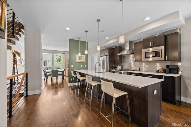 2730 Hooker St, Denver, CO 80211 - kitchen featuring wall chimney range hood, appliances with stainless steel finishes, light countertops, a breakfast bar, and backsplash