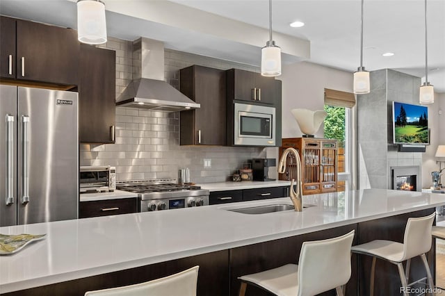 2730 Hooker St, Denver, CO 80211 - kitchen featuring wall chimney exhaust hood, stainless steel appliances, light countertops, a kitchen bar, and decorative backsplash