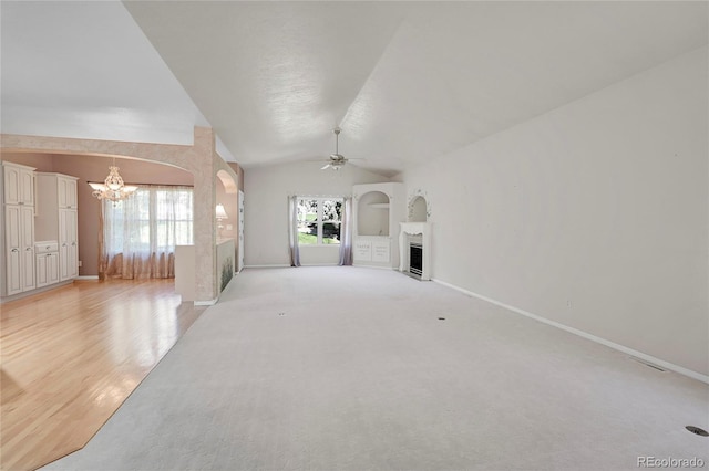 unfurnished living room featuring light carpet, ceiling fan with notable chandelier, and vaulted ceiling